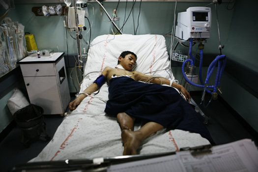 A boy who fell down and was knocked unconscious while playing with friends lies injured in the ICU unit at Gaza's al-Shifa Hospital. Because of the siege, even routine injuries have been difficult to treat.