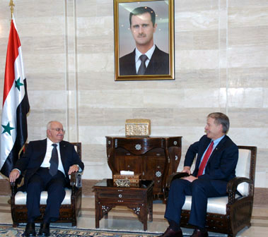 Suncor CEO Richard L. George (right) with former Syrian Prime Minister Mohammad Naji Otri. They are under a large portrait of President Bashar Al-Assad in an undated photo. George told CBC's The Current that Suncor was 'not connected to the Assad regime.'