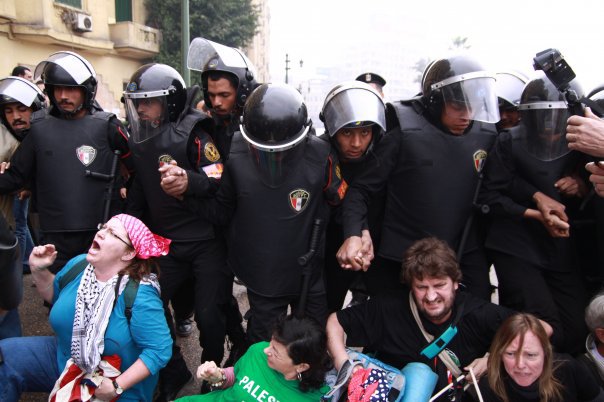 Gaza Freedom March protest occupies part of Tahrir Square in downtown Cairo,: seated protesters with a line of riot police.