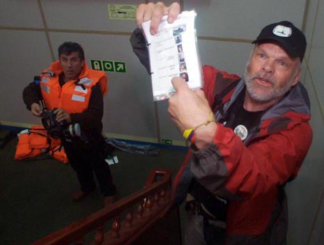 Kevin Neish standing on the stairs between the bridge deck and the boat deck of the Mavi Marmara in May 2010. He is holding a passenger list taken from an Israeli commando's back pack. Photo: www.culturesofresistance.org