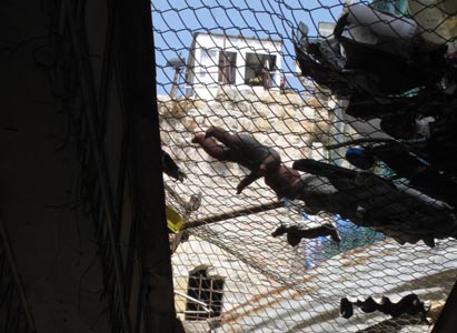 'I look up at a net hanging above the souk. It’s full of garbage and other debris. The Jewish settlers, who number about 500, have built homes above the market street. I am told the net is to protect the Palestinians below.' Photo: Rachel Marcuse.