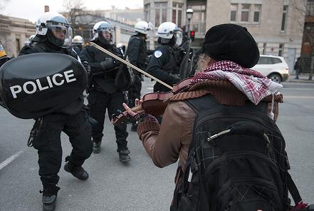 Photo by Darren Ell (http://www.darrenell.com/). Protester plays violin as Montreal riot police advance at annual protest against police brutality in Montreal, 15/03/2012.