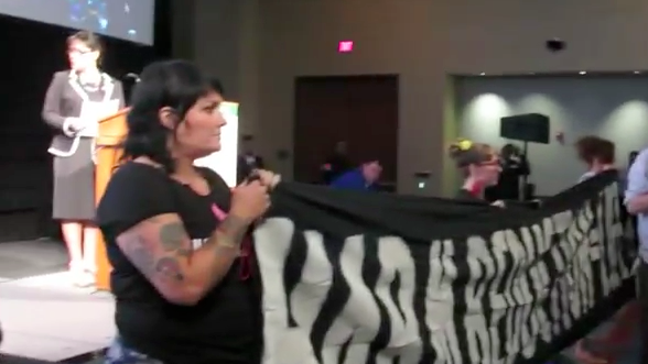 Activists held a banner and others in the audience turned their backs.