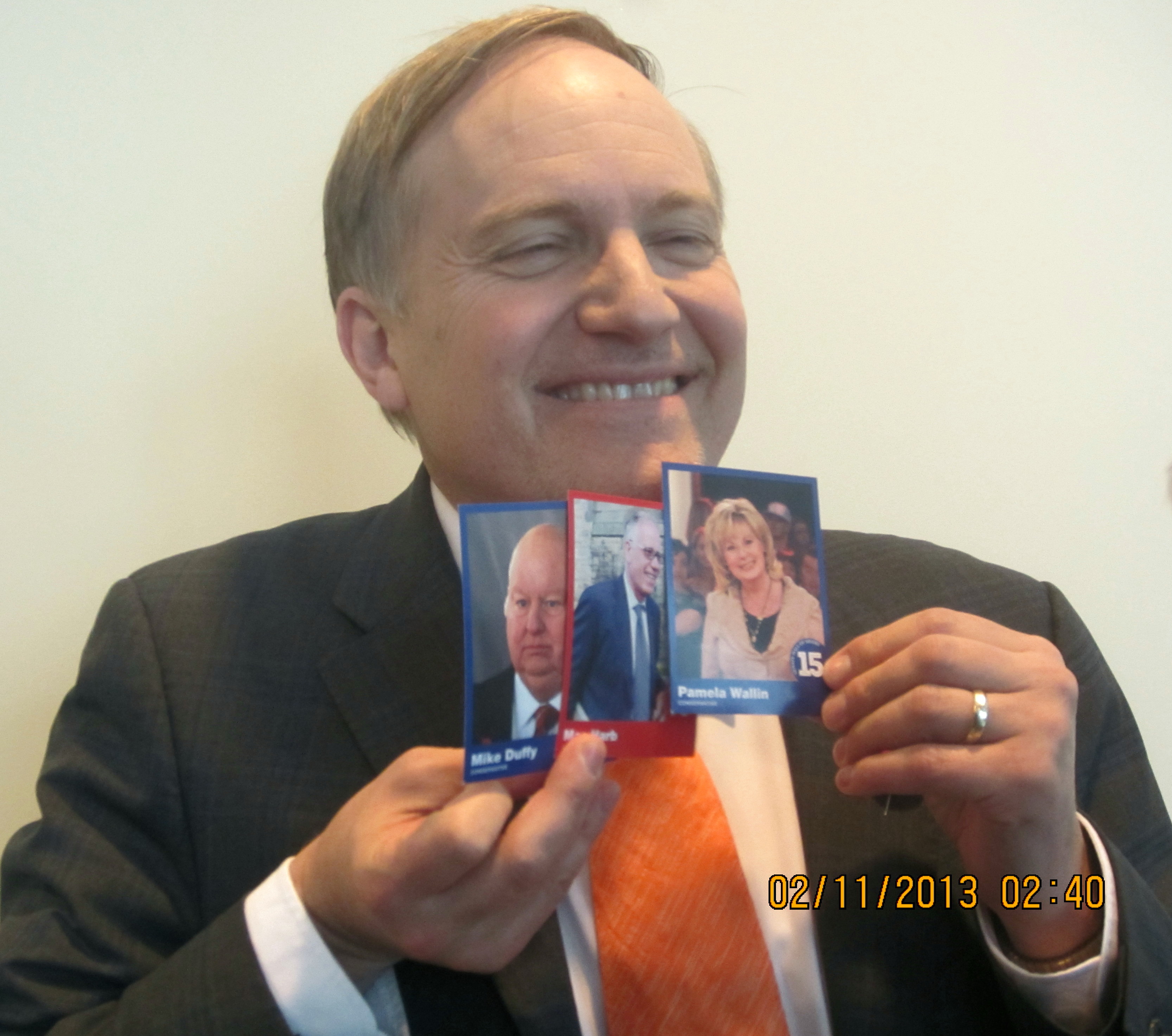 MP Peter Julian holds up trading cards showing Senators