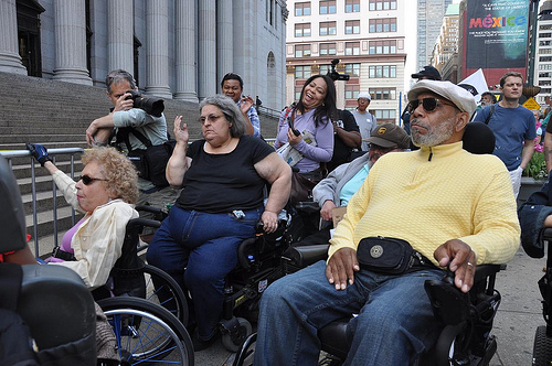 a group of folks with physical disabilities on a city street at a protest