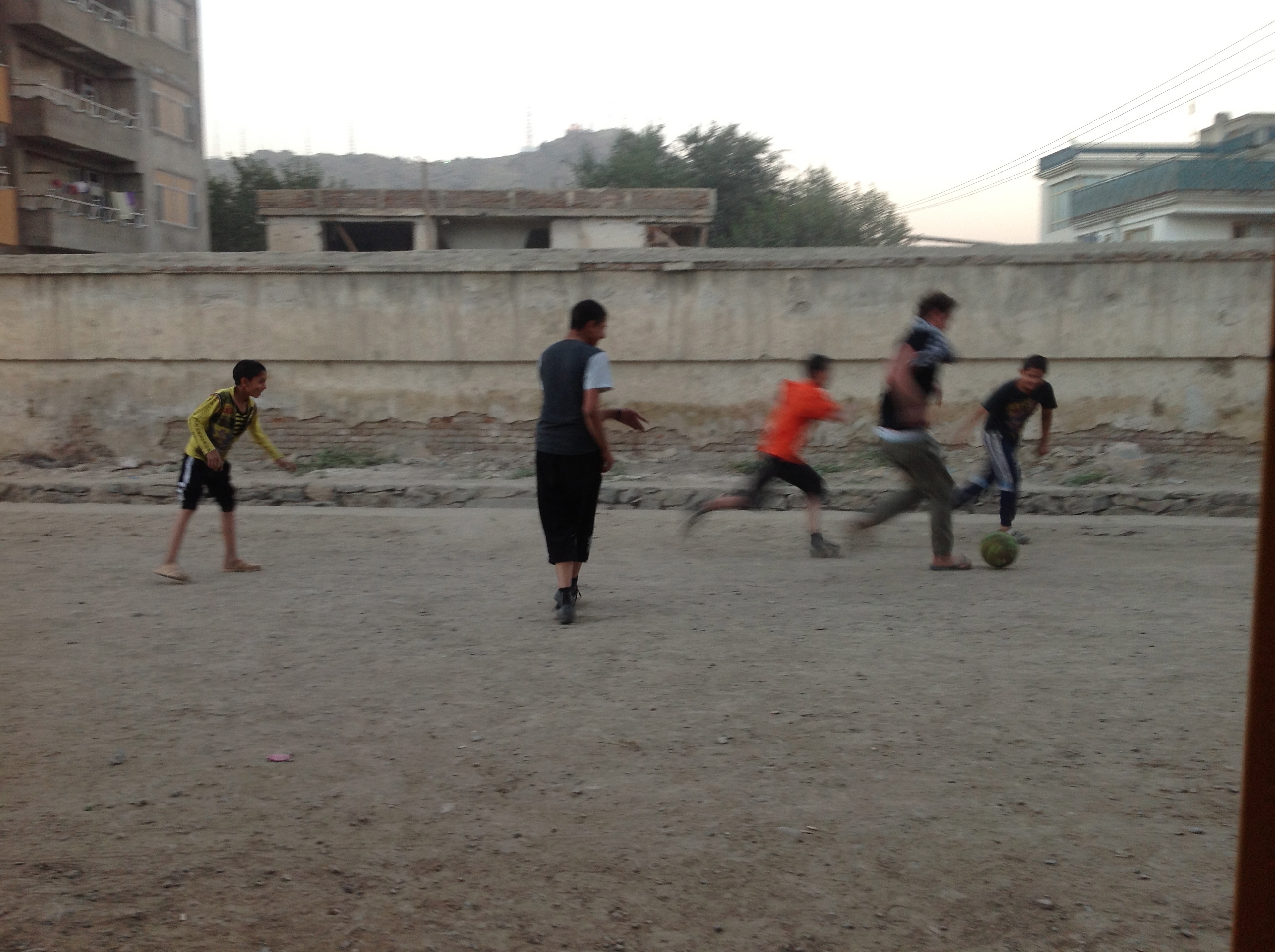 Boys playing soccer in the road