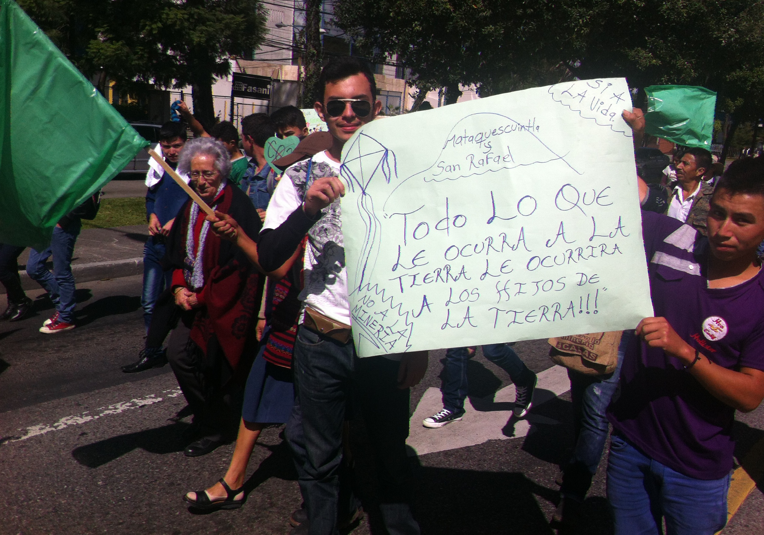 Youth holding sign: Todo lo que ocurra a la tierra, la ocurrira a los hijos de l