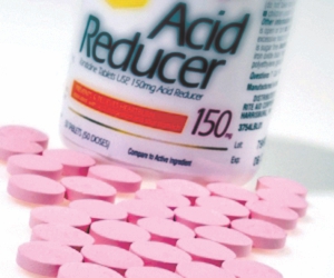 Bottle of antacid pills with pink pills spilled on table