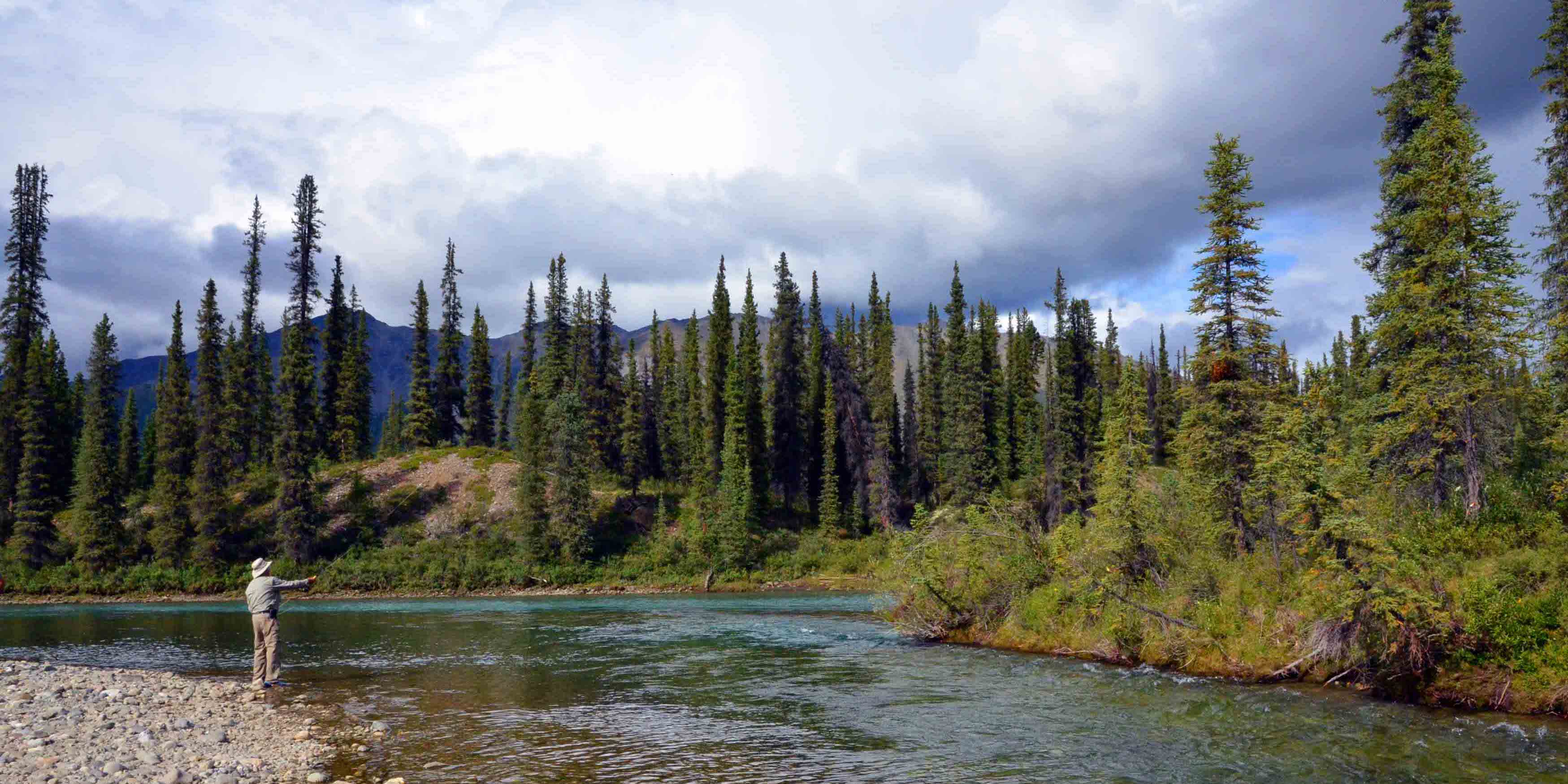 David Suzuki tests the green waters of the Hart River.