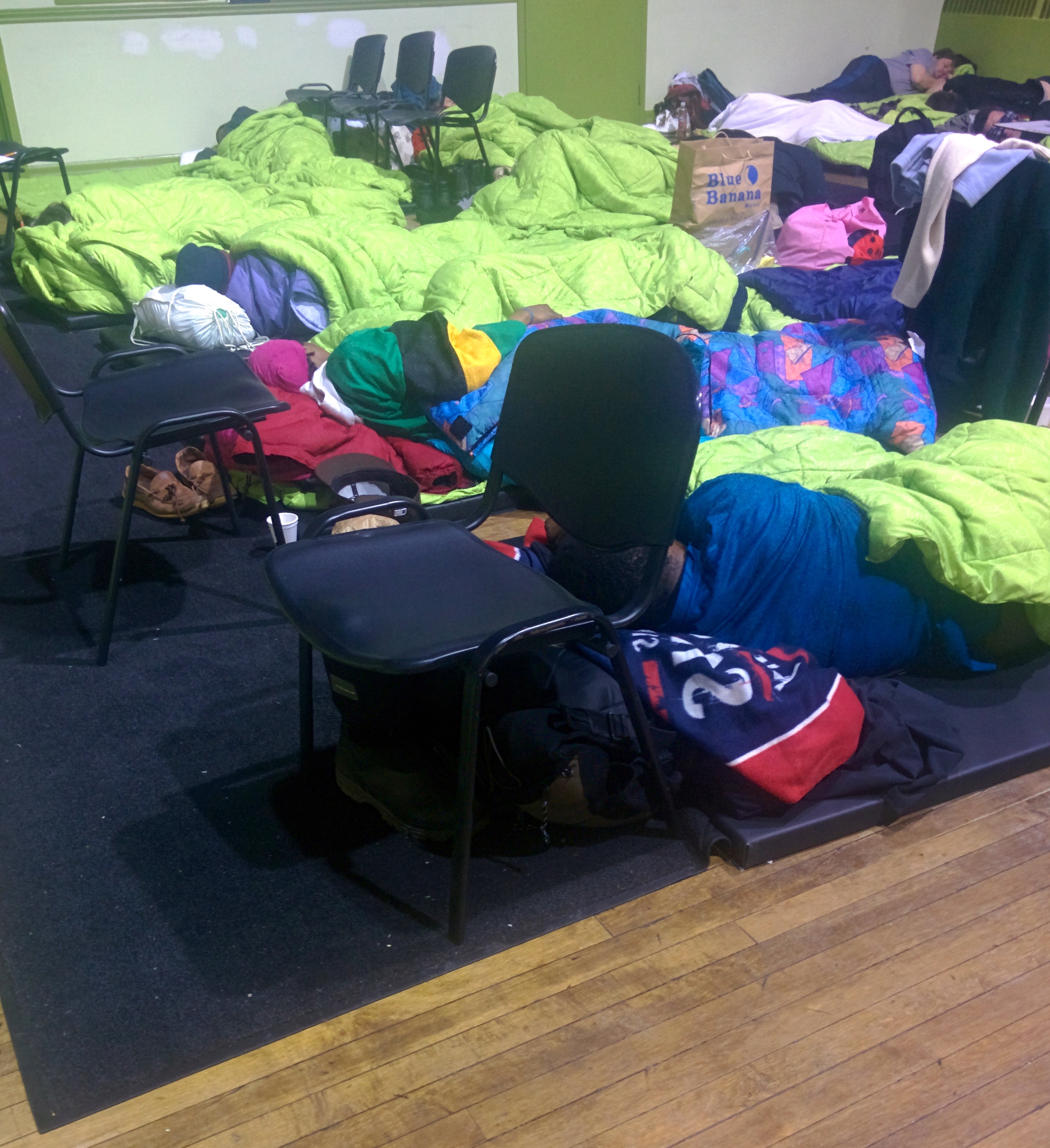 Lime green blankets, donated by PanAm games cover the mats on a floor in a city warming centre.