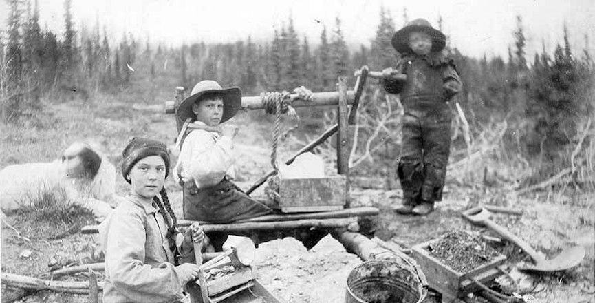 Three children operating rocker at a gold mine on Dominion Creek, Yukon Territory. Image: Wikimedia Commons/Eric A. Hegg Photographs