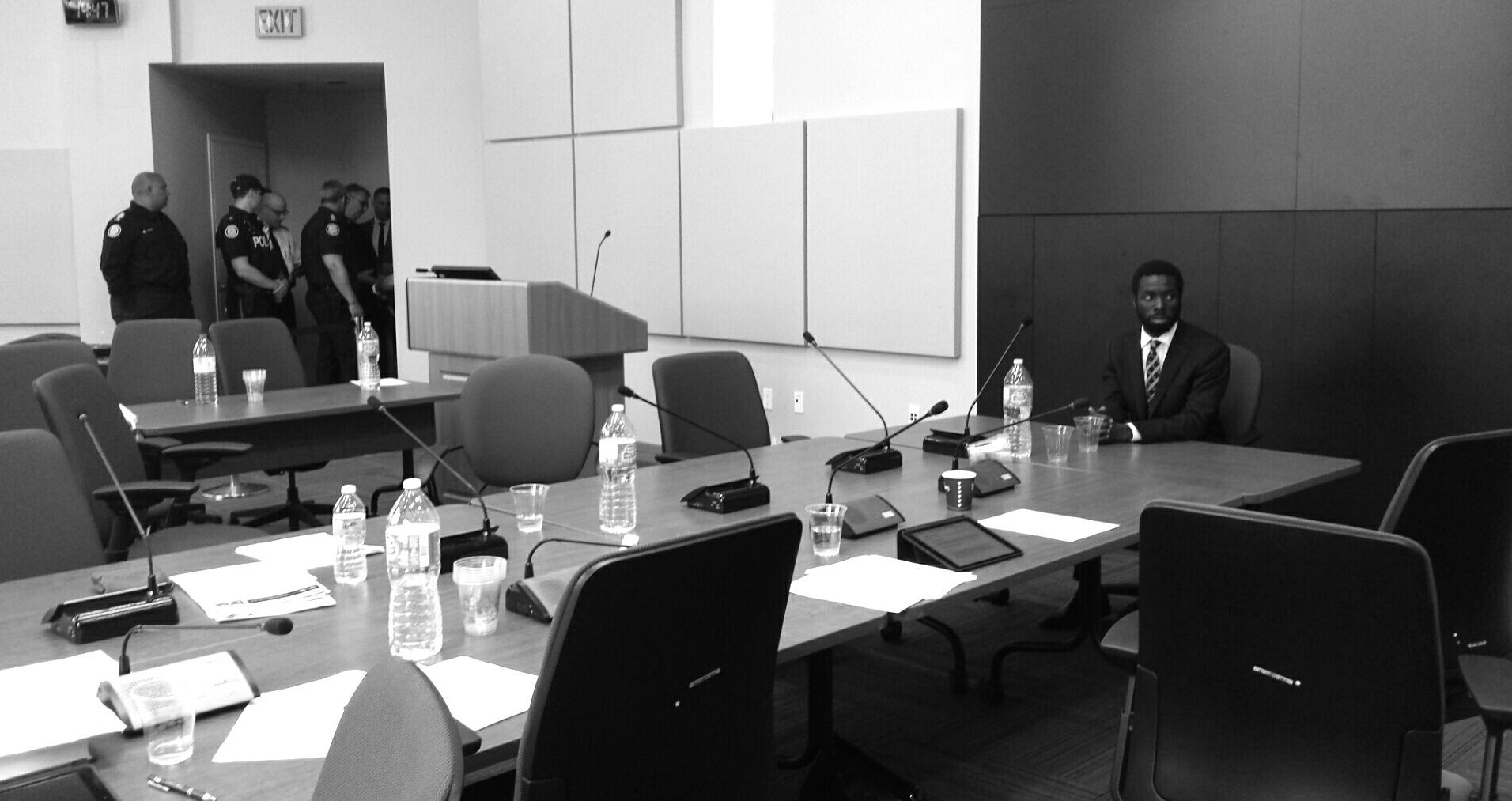 Desmond Cole sits at Toronto Police Services Board table. Used courtesy of @pangmeli on Twitter.