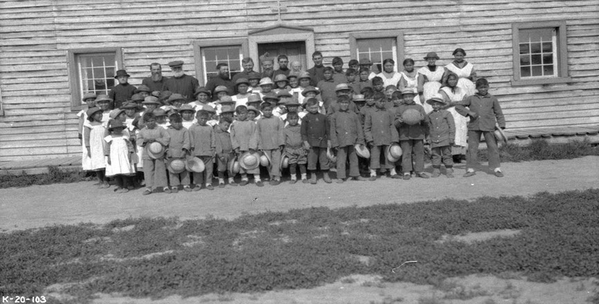 Officials and schoolchildren outside Providence Mission Indian Residential School. LibraryArchives/flickr