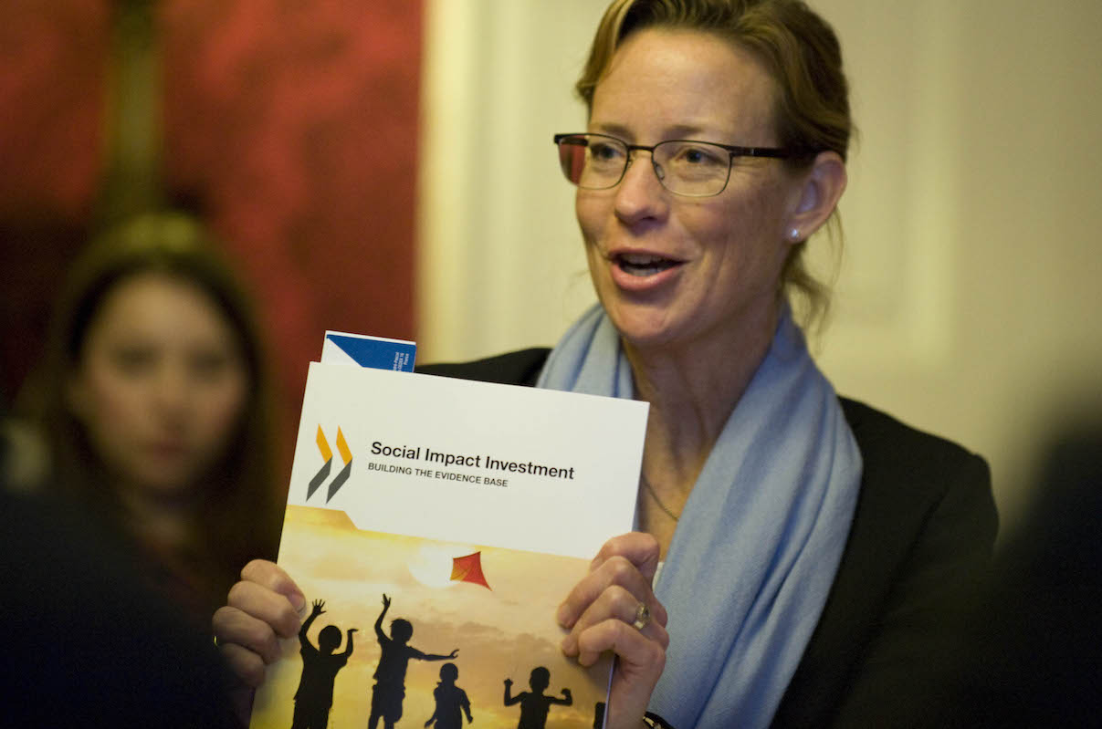 Karen Wilson of the OECD holds up report on social impact investment. Photo: Cabinet Office/Flickr