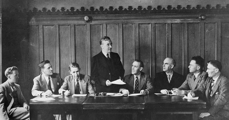 Federal CCF Caucus, 1942. M.J. Coldwell is the new leader after Woodsworth's death. Left to right, Tommy Douglas, George Castleden, Angus MacInnis, Coldwell, Clarie Gillis , Joe Noseworthy, Sandy Nicholoson, and Percy Wright. Photo: C.C.F. / Library and Archives Canada / C-000314 via Wikimedia Commons