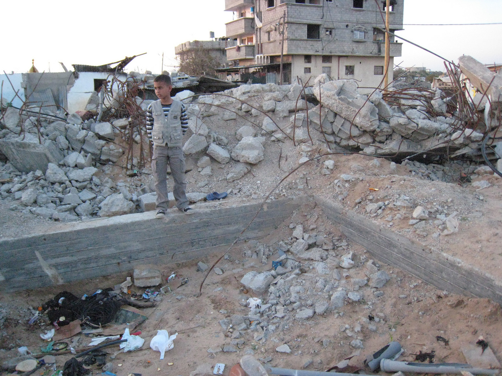 Boy stands by building rubble in Palestine. Photo: Grassroots International/Flickr