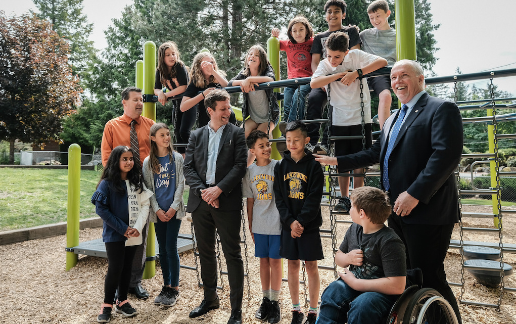 John Horgan stands with children on playground. Photo: Province of British Columbia/Flickr