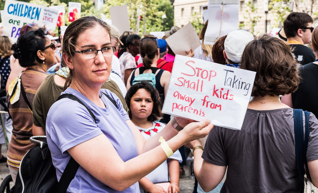 Woman with protest sign reading "Stop Taking Small Kids Away from Parents." Photo: Geoff Livingston/Flickr