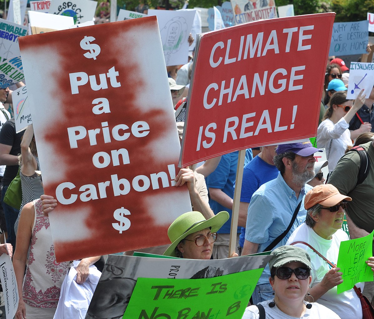 Placards "Put a price on carbon" and "Climate change is real," at the People's Climate March 2017. Photo: Edward Kimmel/Wikimedia Commons