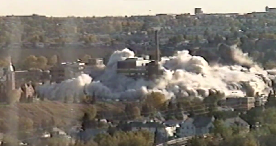 The Calgary General Hospital is exploded into rubble on Oct. 4, 1998, a symbolically spectacular example of Conservative mismanagement of health care in Alberta. Photo: Screenshot of video.