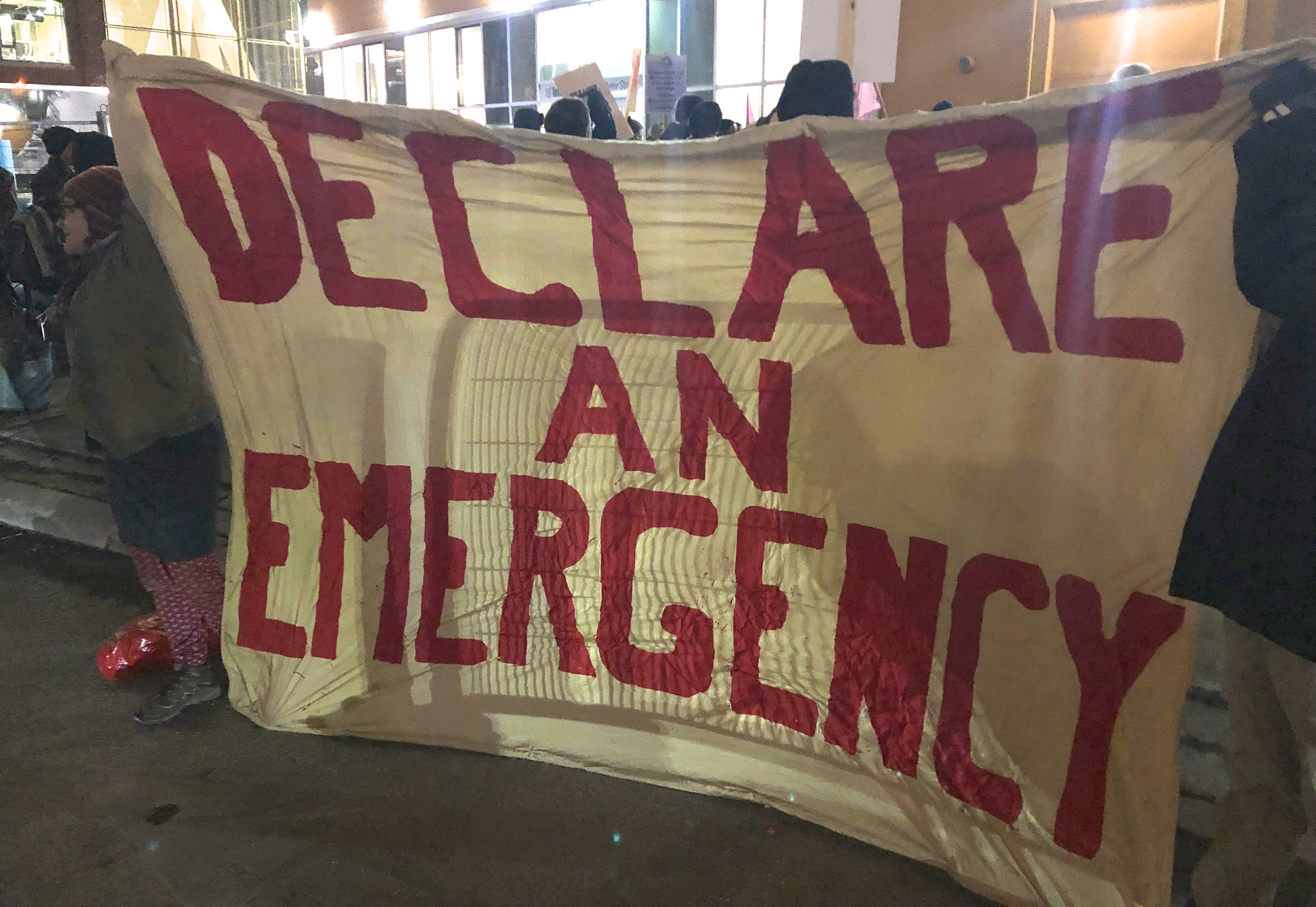 Activists hold a banner at a vigil hat says "Declare an Emergency." Image: Cathy Crowe