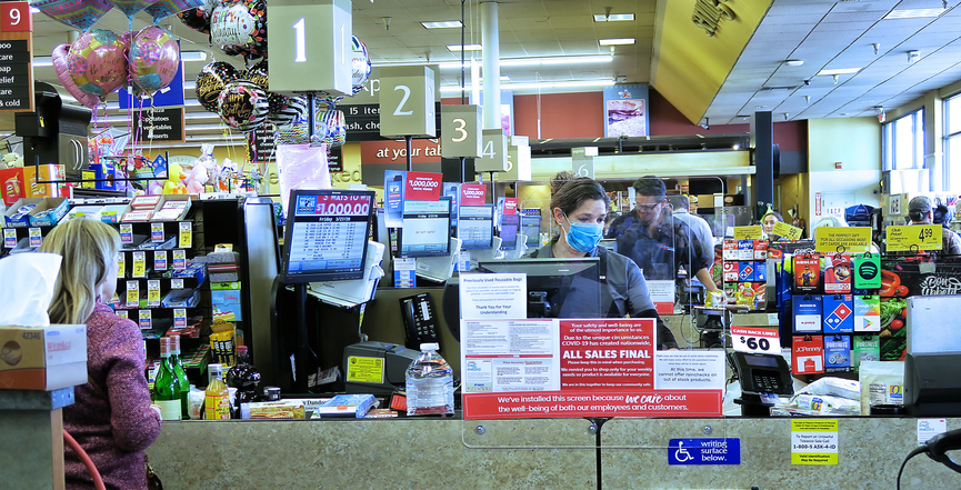 A supermarket checker works behind a plastic shield. Image: Russ Allison Loar​/Flickr