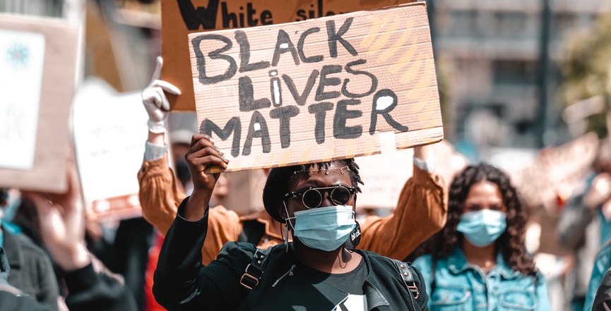 A woman holds a Black Lives Matter sign. Image: Joan Villalon/Unsplash