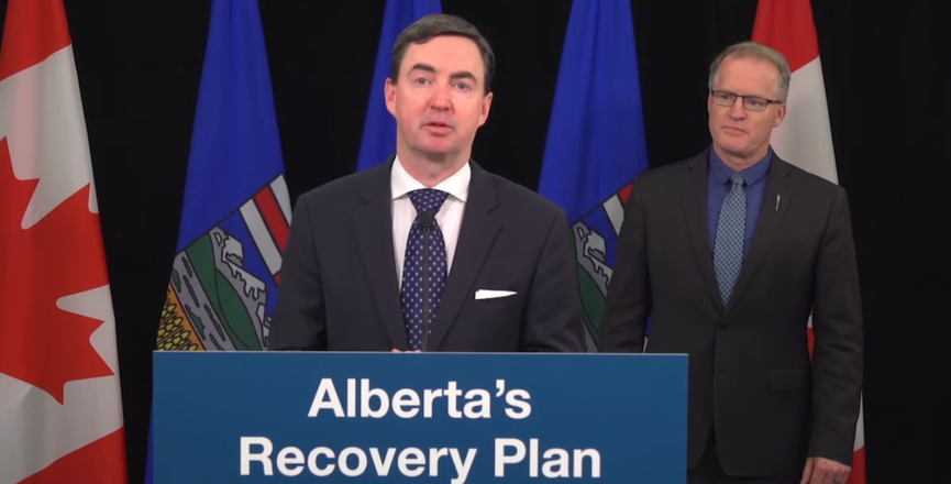 Alberta Labour Minister Jason Copping addressing yesterday's "embargoed news conference" as "red tape reduction minister" Grant Hunter looks on. Image: Screenshot of Alberta Government video