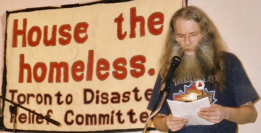 Dri giving a speech at a CAW (now UNIFOR) meeting in front of a banner that says "House the Homeless. Toronto Disaster Relief Committee." Image: Cathy Crowe