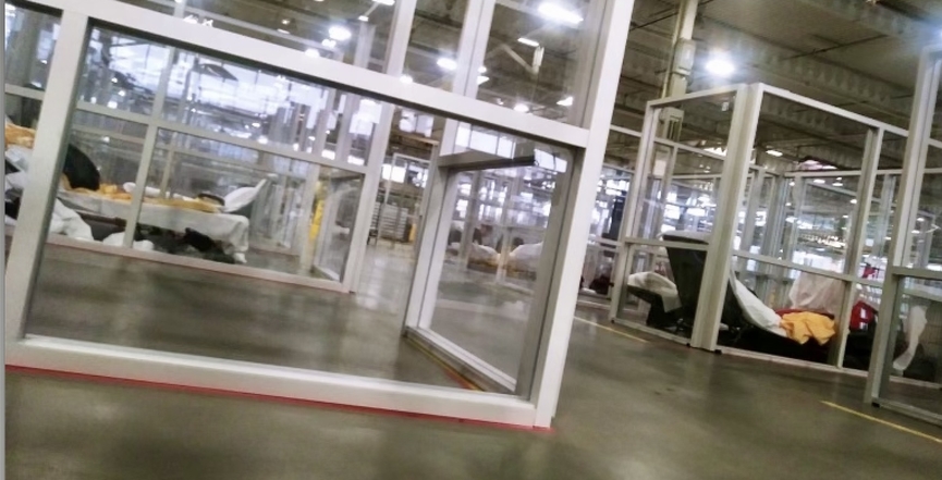 Image of plexiglass sleeping cubicles in Better Living Centre. Lawn type furniture cots substitute for beds. Image: Cathy Crowe