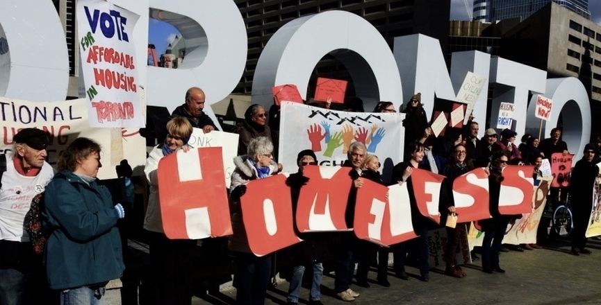 Protesters hold signs about homelessness in front of the Toronto sign at Toronto City Hall (Image: Photo by Cathy Crowe)