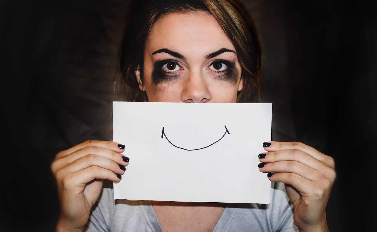 Woman holds happy face sign. Image credit: Sydney Sims/Unsplash