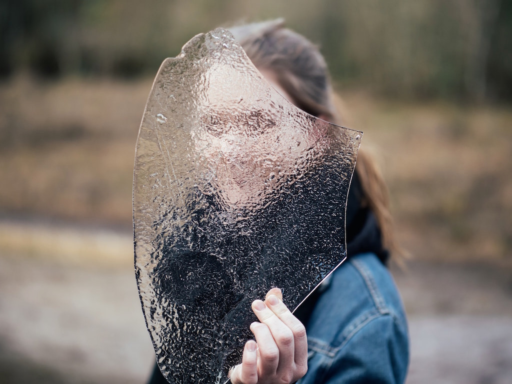 Woman covering face with frosted glass. Image credit: Jamie Street/Unsplash