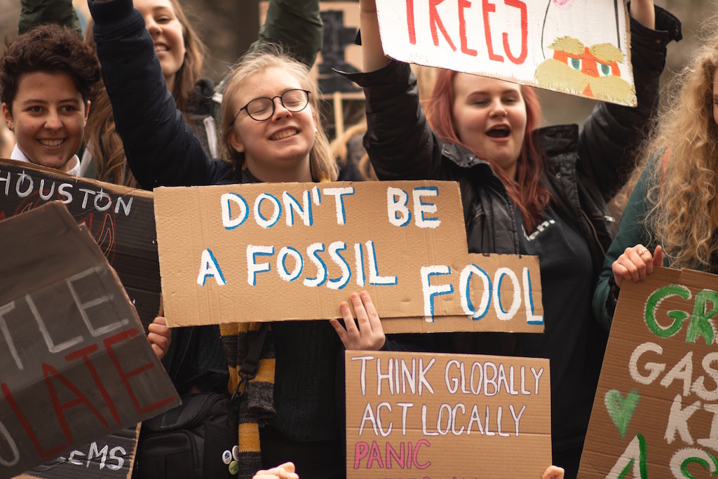 Youth hold signs protesting fossil fuels. Image credit: Callum Shaw/Unsplash