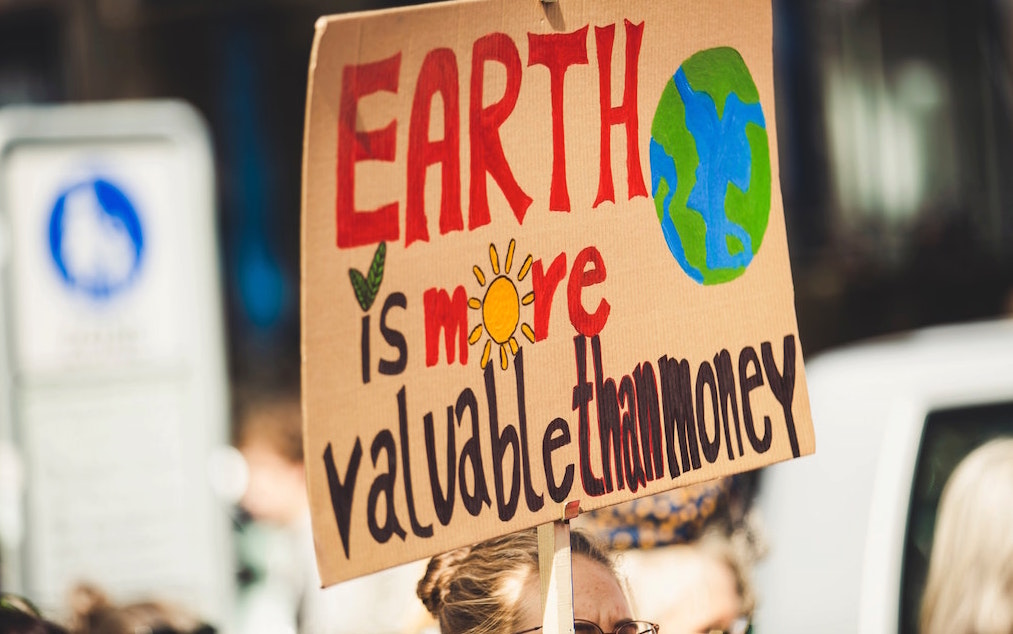 Protest sign reading "Earth is more valueble than money." Image credit: Markus Spiske/Unsplash