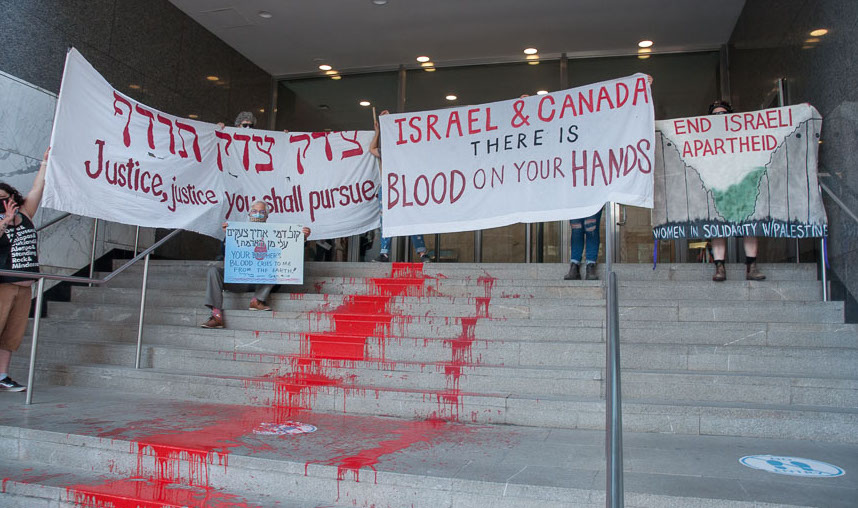 Rabbi David Mivasair sits next to paint-covered steps outside Israeli consulate. Image: World BEYOND War Canada/Twitter