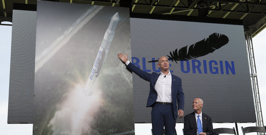 Billionaire Jeff Bezos gestures at a picture of a rocket. Image: NASA Kennedy/Flickr