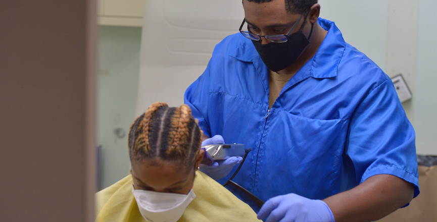 A haircut with pandemic measures, as the stylist and client both wear masks. Image: Navy Medicine/Flickr