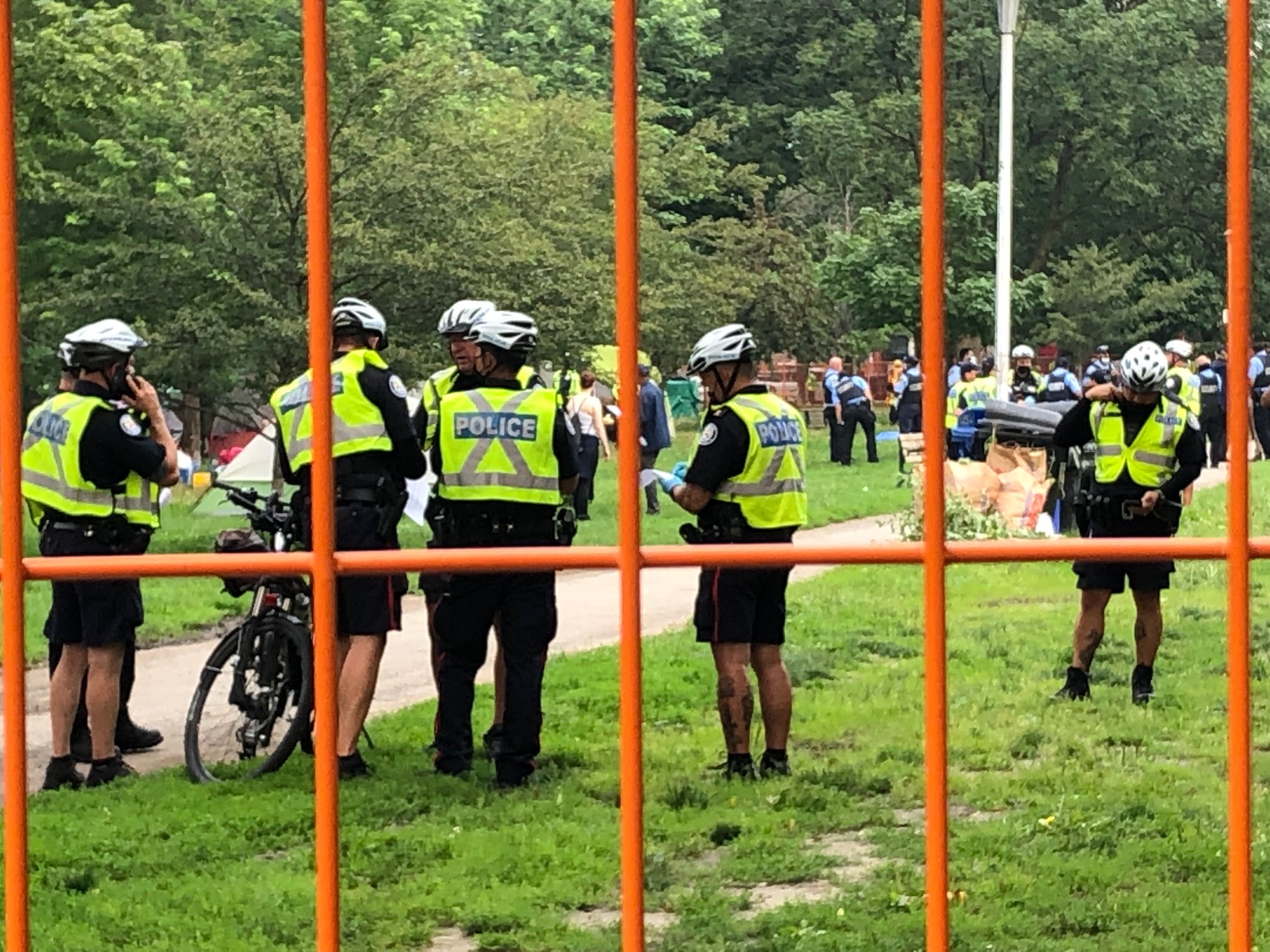 Toronto police and security personnel are seen through an orange fence during the eviction. Image: Rafi Aaron/Used with permission