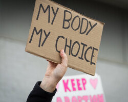Photo of a pro-choice protester holding up a sign reading my body, my choice.