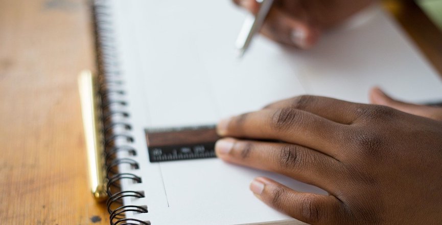 A Black student's hands drawing in a notebook with a ruler and pencil. Image: StockSnap/Pixabay