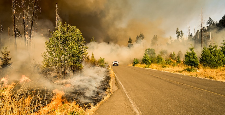 A truck drives through a wildfire. Image: Marcus Kauffman/Unsplash