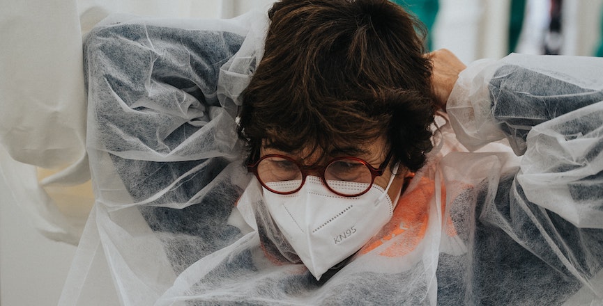 A health-care worker at a COVID-19 testing site replaces her gown and mask. Image: Mat Napo/Unsplash