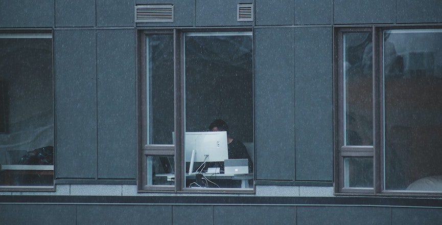 A person on a computer and tablet being watched through a window. Image: Sigmund/Unsplash