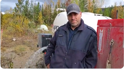 An RCMP officer -- Officer Charney -- empties water tanks at the Gidimt’en Checkpoint. (Image: Gidimt’en Checkpoint/Twitter)