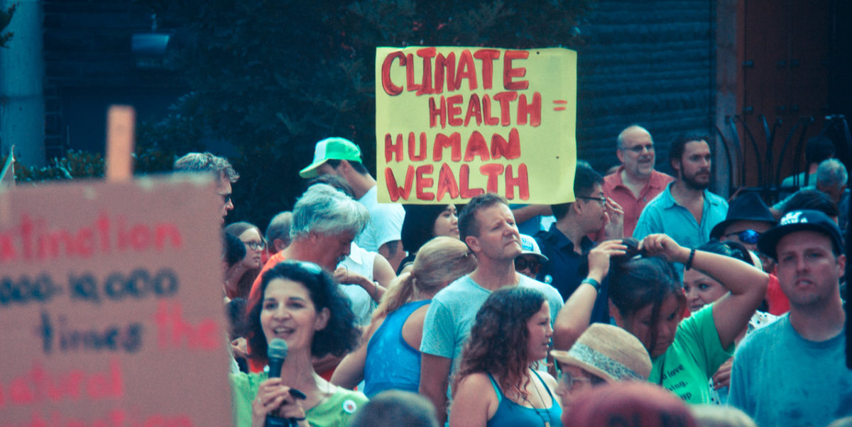 A climate marcher holds up a sign that reads "climate health = human health"