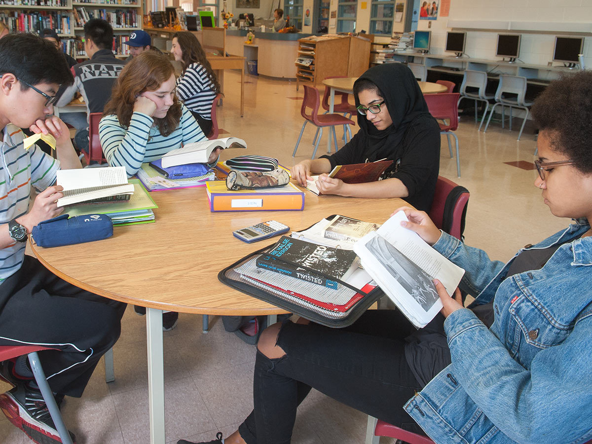 High School students sitting and reading in a library.