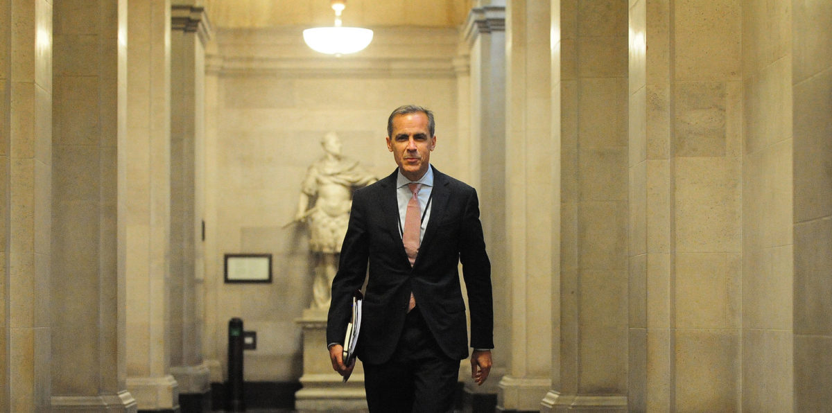 Mark Carney walks down a marble hallway with files under his arm.