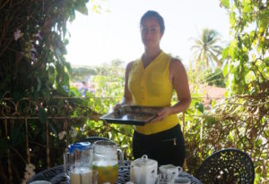 Milgaro, who works as a server at Casa Larabi, stands in front of a table set with an assortment of foods and drinks.