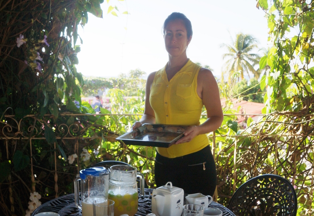 Milgaro, who works as a server at Casa Larabi, stands in front of a table set with an assortment of foods and drinks.